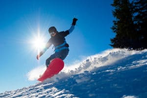 Snowboarder Riding Red Snowboard on sunny day on Gunstock Mountain